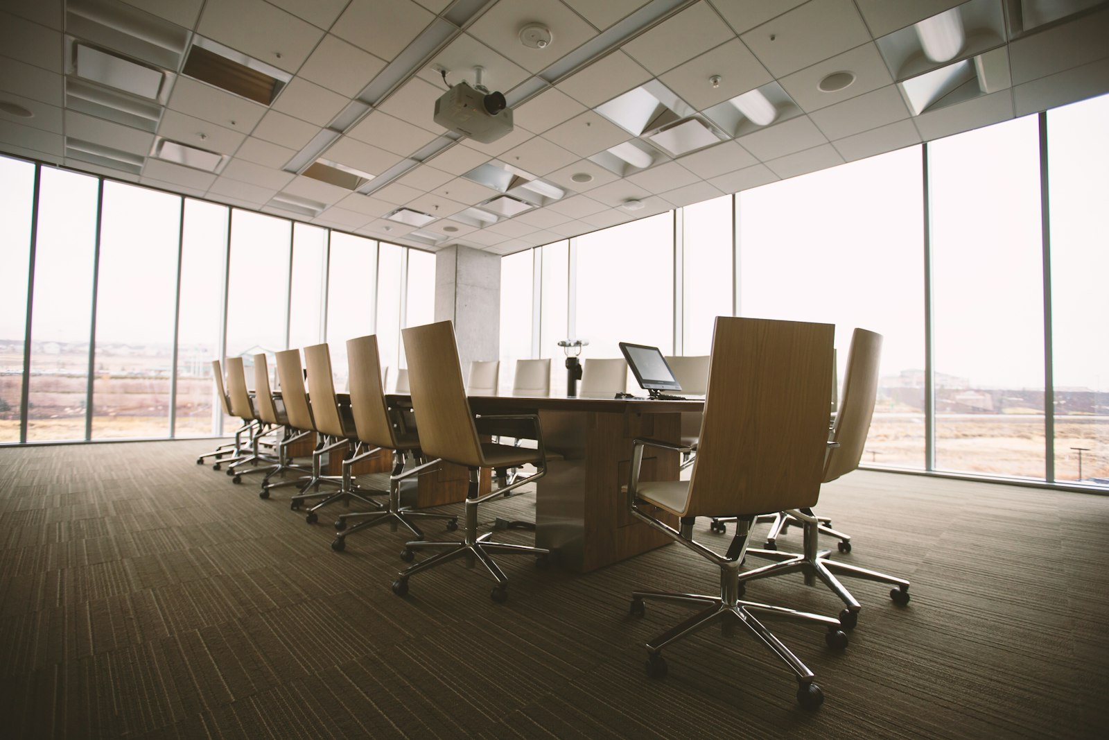 Empty boardroom table in front of floor-to-ceiling windows